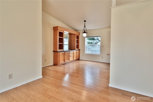 unfurnished living room with light wood-style flooring, baseboards, and vaulted ceiling