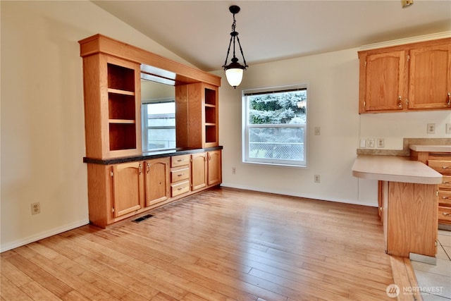 unfurnished dining area featuring visible vents, baseboards, light wood-style flooring, and vaulted ceiling