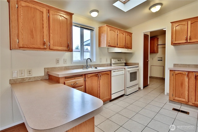 kitchen featuring a sink, under cabinet range hood, white appliances, a peninsula, and a skylight