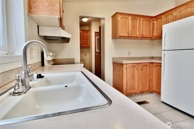 kitchen featuring a sink, freestanding refrigerator, light countertops, light tile patterned floors, and range