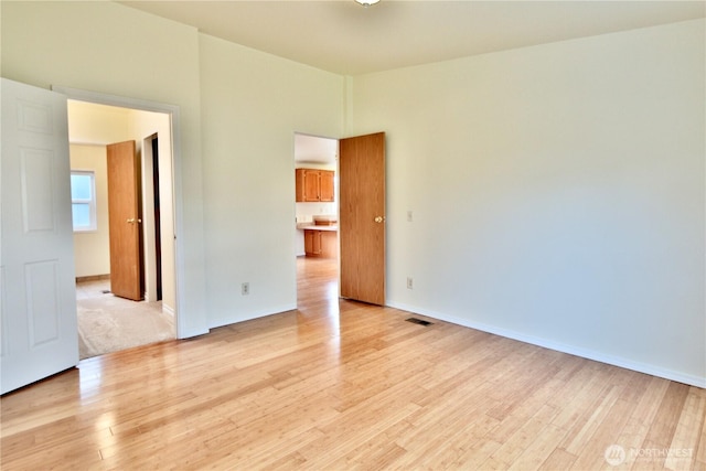 spare room with visible vents, baseboards, and light wood-style floors