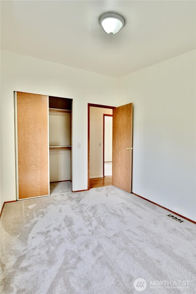 unfurnished bedroom featuring carpet flooring, visible vents, and a closet