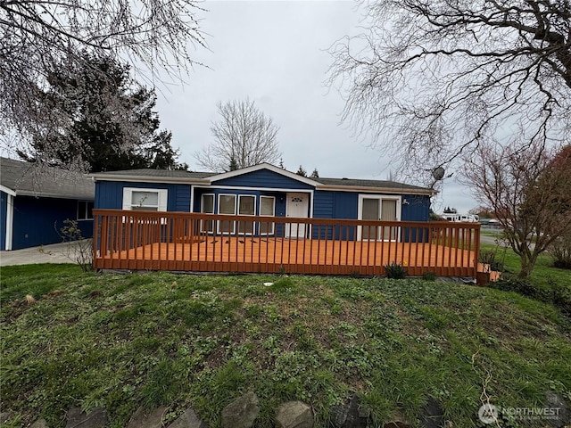 view of front of property with a deck and a front lawn