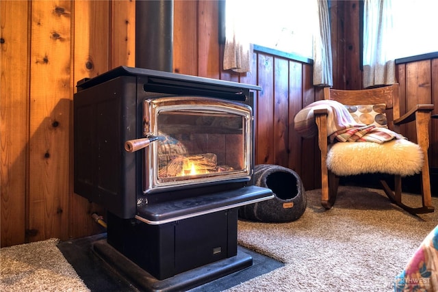 sitting room with wooden walls, a wood stove, and carpet