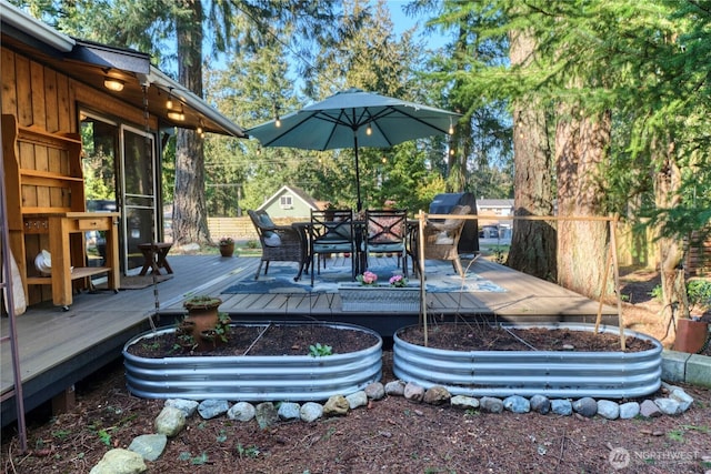 wooden terrace featuring grilling area, outdoor dining area, and a garden