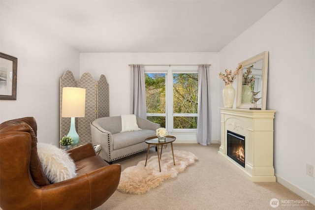 living area featuring carpet floors, a glass covered fireplace, and baseboards