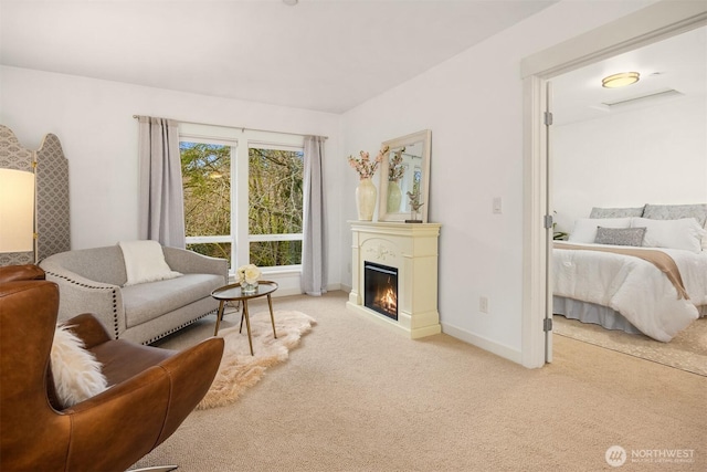 interior space with a glass covered fireplace, light colored carpet, and baseboards