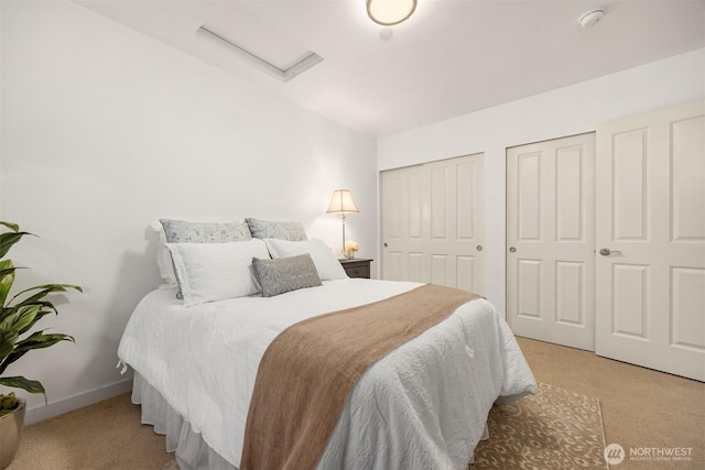 bedroom featuring carpet, attic access, baseboards, and multiple closets