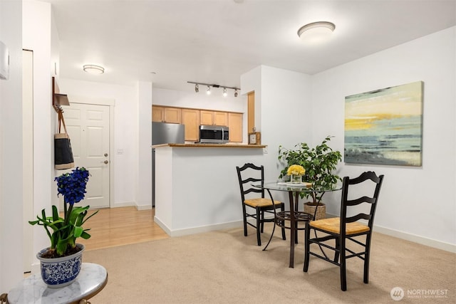 dining area with light carpet, rail lighting, and baseboards