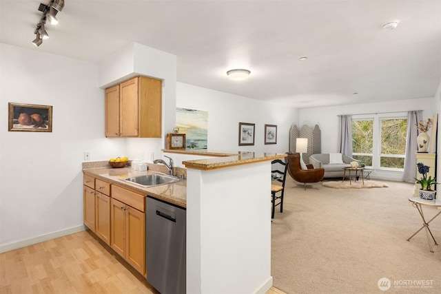 kitchen featuring baseboards, dishwasher, open floor plan, a peninsula, and a sink