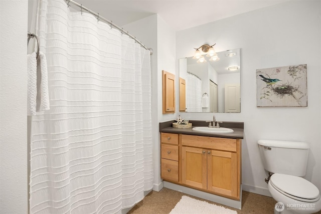 bathroom with toilet, vanity, and baseboards