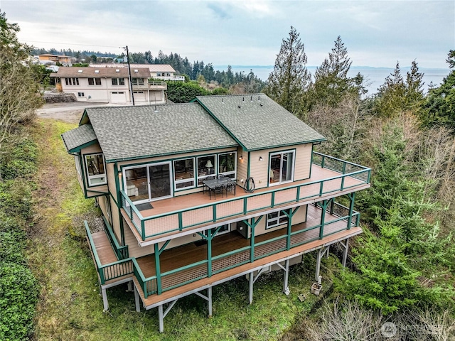 rear view of house featuring roof with shingles and a wooden deck