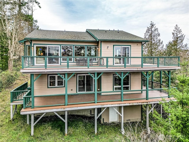 back of house featuring roof with shingles and a wooden deck