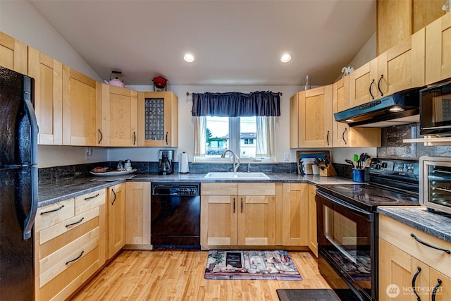 kitchen featuring light wood finished floors, light brown cabinetry, a sink, under cabinet range hood, and black appliances