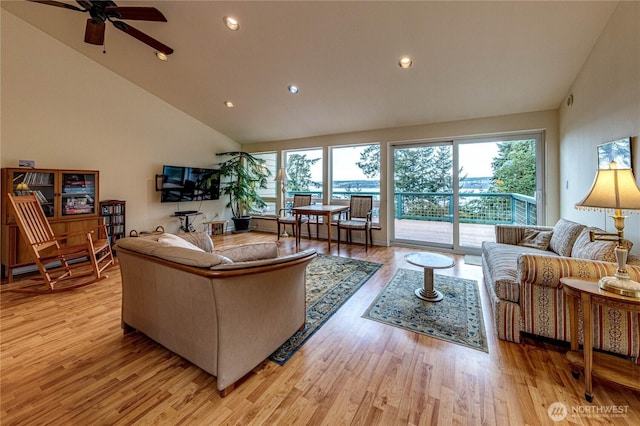 living area with a healthy amount of sunlight, light wood-style floors, and high vaulted ceiling