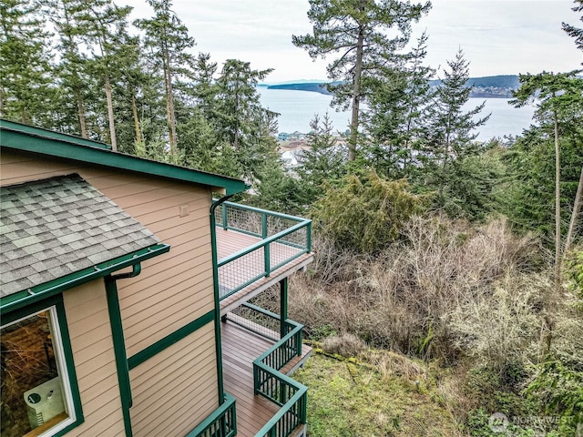 view of side of property with stairs, a deck with water view, and roof with shingles