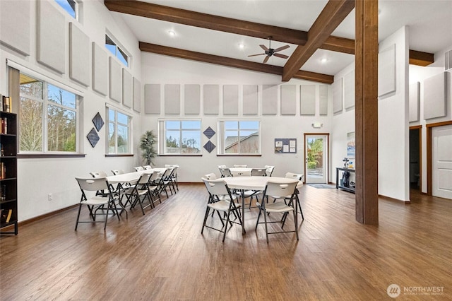 dining area featuring baseboards, a ceiling fan, wood finished floors, beamed ceiling, and a high ceiling