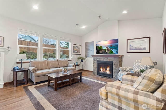 living area with vaulted ceiling, a fireplace, baseboards, and light wood-style floors