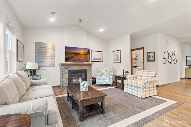 living area with lofted ceiling, a fireplace, baseboards, and wood finished floors