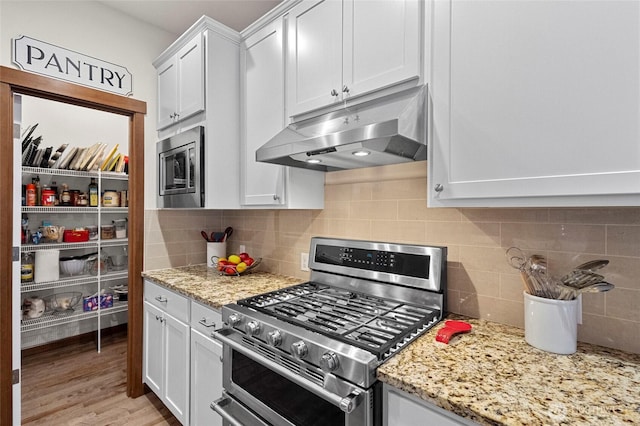 kitchen featuring appliances with stainless steel finishes, backsplash, white cabinetry, and under cabinet range hood