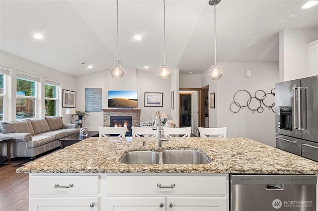 kitchen with open floor plan, stainless steel appliances, a sink, and lofted ceiling