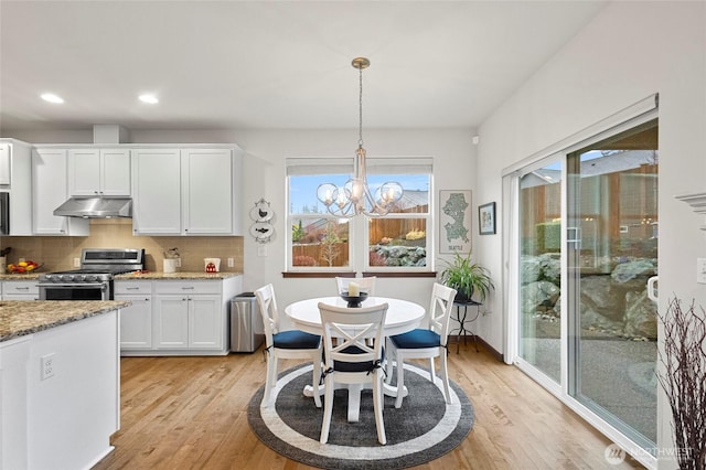 kitchen featuring decorative backsplash, light wood-style floors, white cabinets, stainless steel range with gas stovetop, and under cabinet range hood