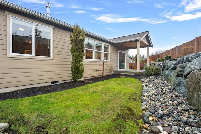 view of side of home featuring a yard and fence