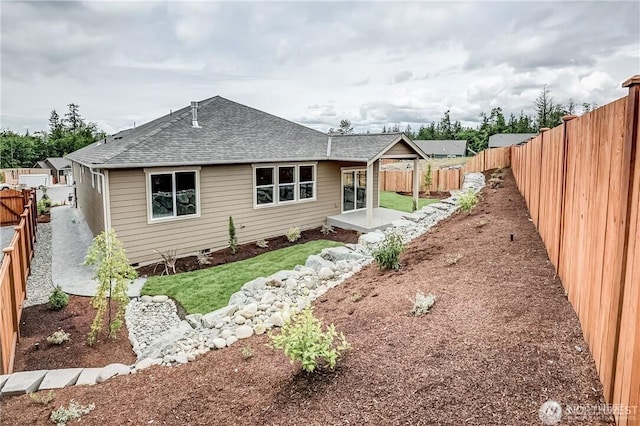 rear view of property with roof with shingles, a patio area, and a fenced backyard