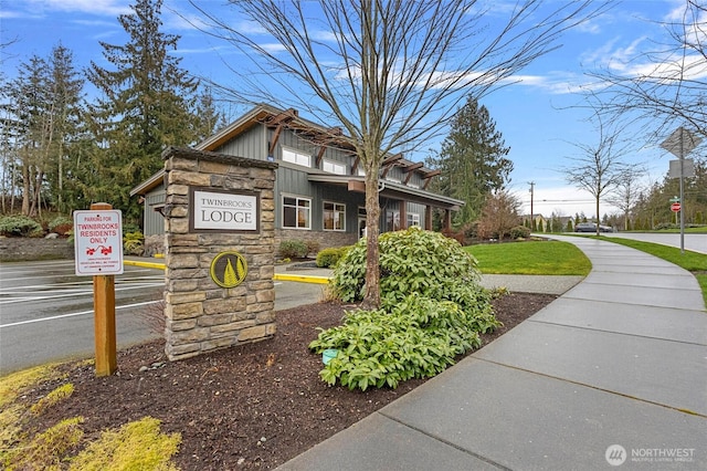 view of side of property with stone siding, uncovered parking, and board and batten siding