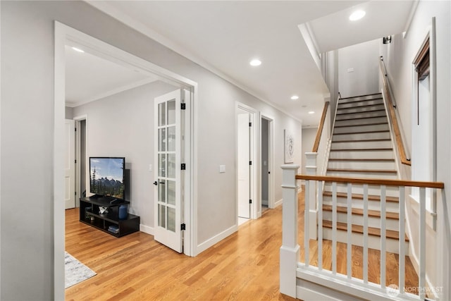 corridor featuring recessed lighting, baseboards, stairs, ornamental molding, and light wood-type flooring