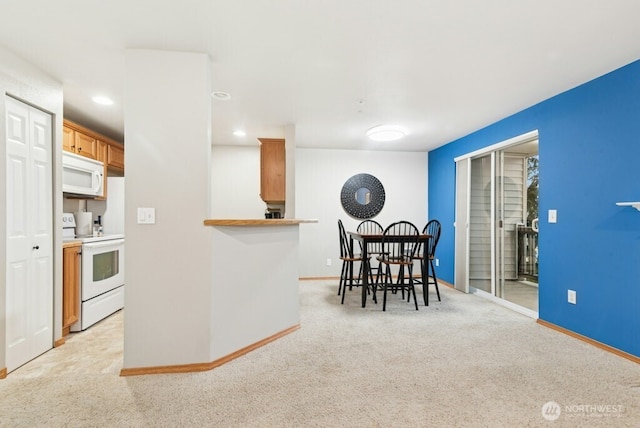 kitchen featuring recessed lighting, white appliances, light carpet, and baseboards