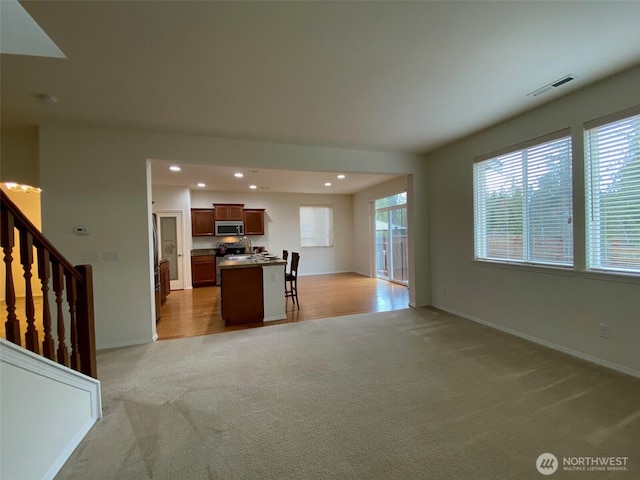 unfurnished living room with light carpet, baseboards, visible vents, and recessed lighting