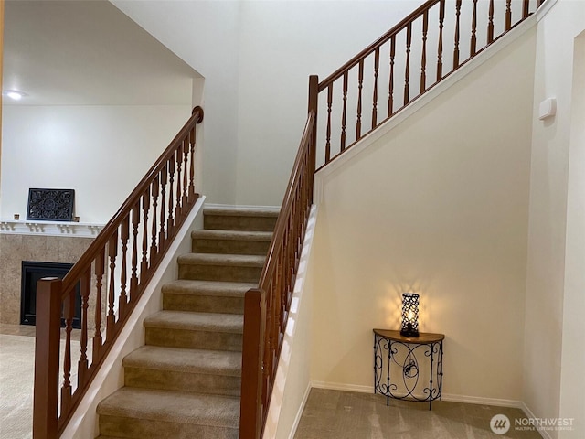 stairs with carpet, baseboards, and a premium fireplace