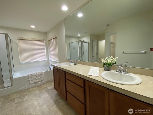 bathroom featuring a garden tub, double vanity, a stall shower, and a sink