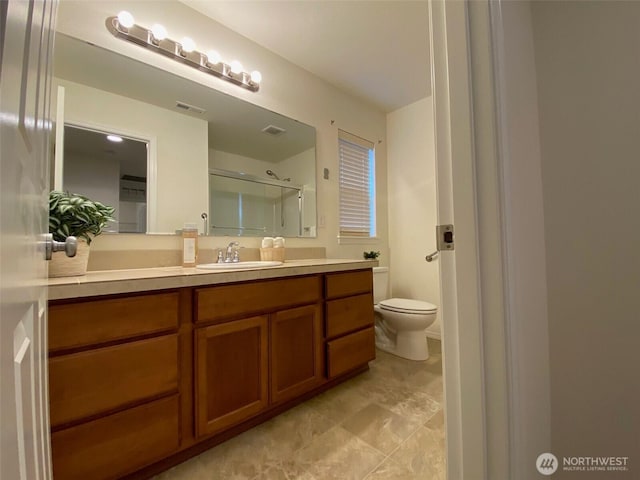 bathroom featuring toilet, a shower with shower door, visible vents, and vanity