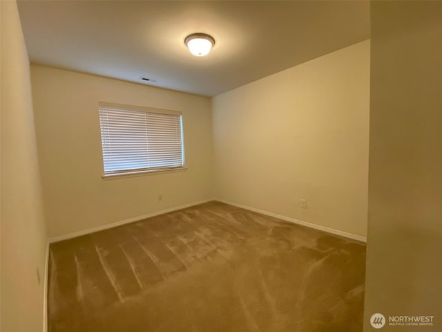 carpeted spare room with visible vents and baseboards