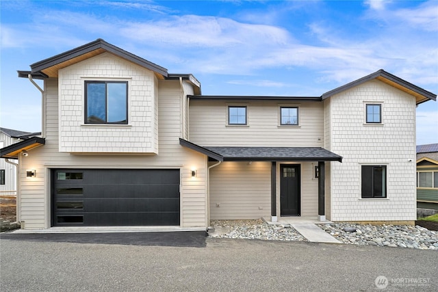 view of front of property featuring driveway, an attached garage, and roof with shingles