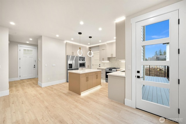 kitchen with a center island, hanging light fixtures, stainless steel appliances, light countertops, and light wood-type flooring