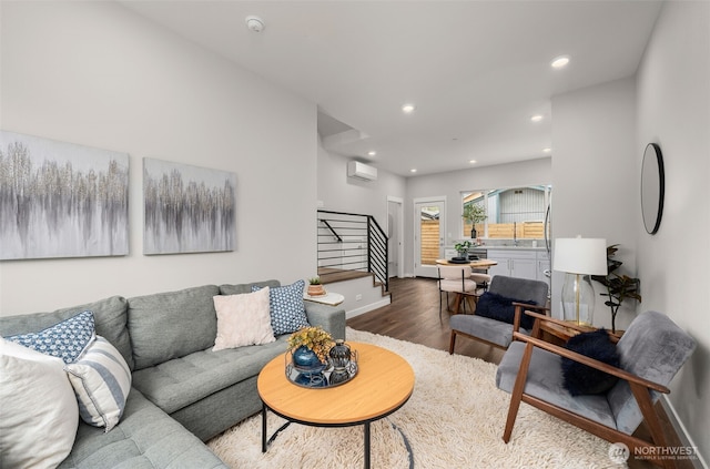 living area featuring recessed lighting, wood finished floors, a wall mounted air conditioner, baseboards, and stairs