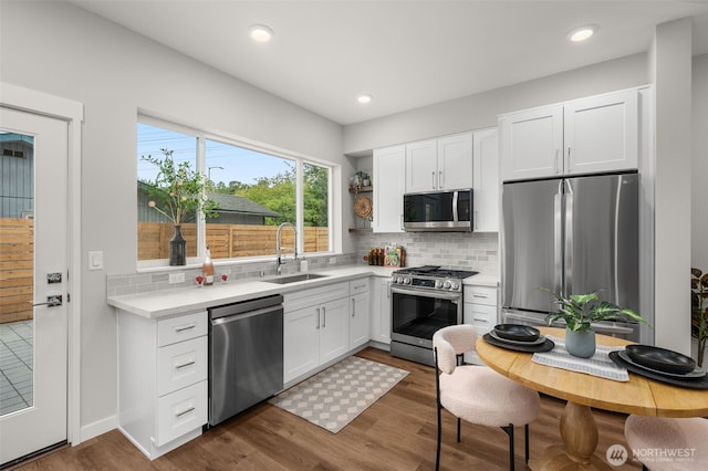 kitchen with a sink, white cabinetry, light countertops, appliances with stainless steel finishes, and decorative backsplash