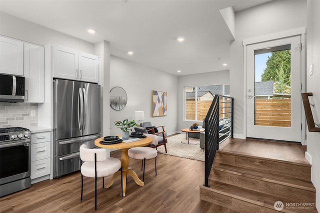 kitchen featuring dark wood finished floors, decorative backsplash, white cabinets, appliances with stainless steel finishes, and light countertops