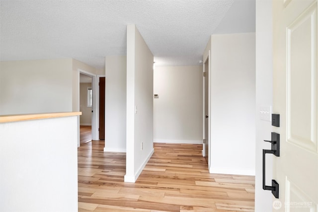 interior space featuring a textured ceiling, light wood-style flooring, and baseboards