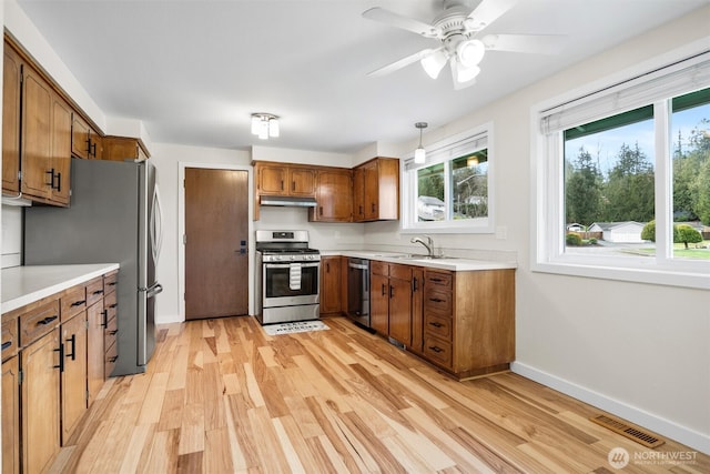 kitchen featuring stainless steel appliances, a sink, visible vents, light wood-style floors, and brown cabinets