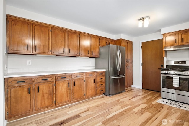 kitchen with under cabinet range hood, stainless steel appliances, and brown cabinetry