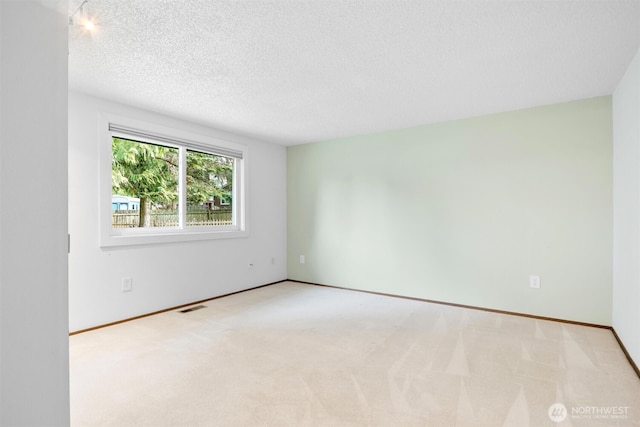 unfurnished room featuring carpet floors, visible vents, a textured ceiling, and baseboards