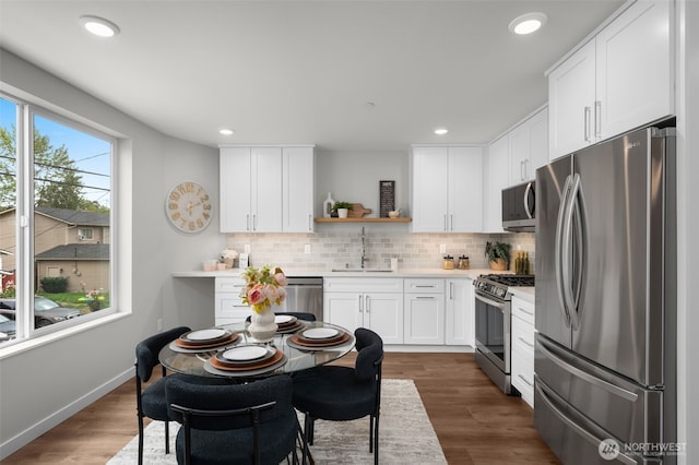 kitchen with a sink, white cabinetry, light countertops, appliances with stainless steel finishes, and open shelves