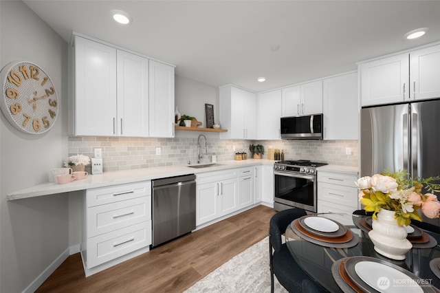 kitchen with white cabinets, appliances with stainless steel finishes, wood finished floors, open shelves, and a sink