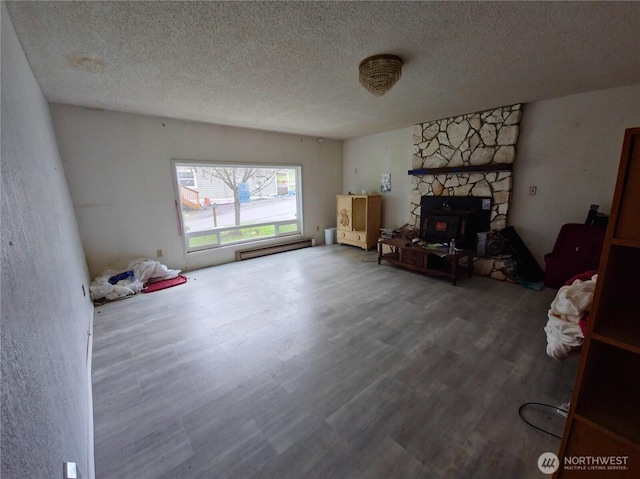 living room with a baseboard heating unit, a textured ceiling, and wood finished floors