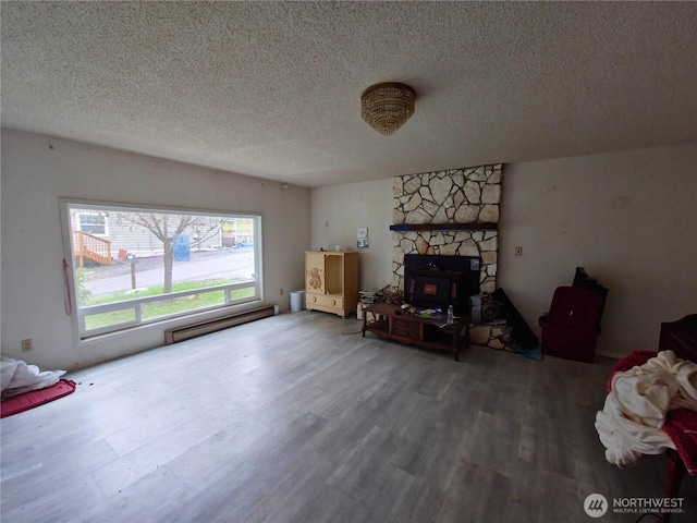 living area featuring a baseboard heating unit, a textured ceiling, and wood finished floors