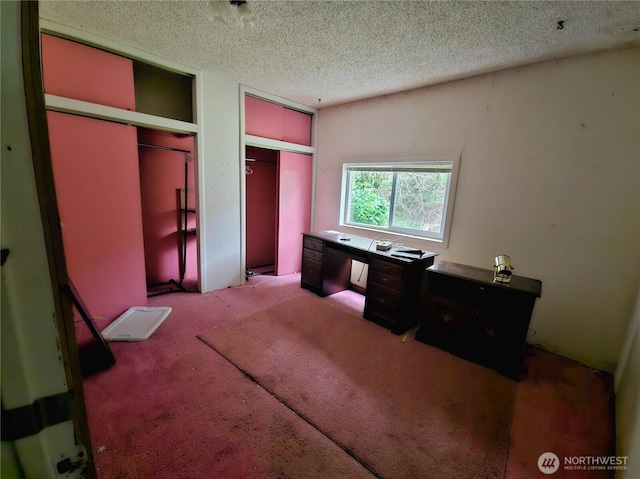 carpeted bedroom featuring multiple closets and a textured ceiling